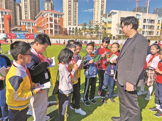 洛江区附属小学小记者用纸和笔记录运动会精彩瞬间